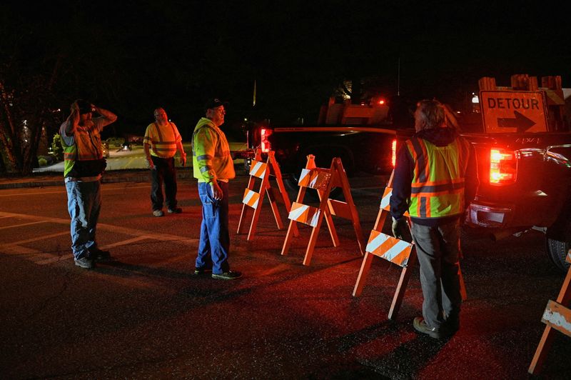 &copy; Reuters. Workers set down detour signs while police organize around Lisbon High School as an active search for a gunman is underway after Lewiston's deadly mass shootings, in Lisbon, Maine, U.S. October 26, 2023.  REUTERS/Nicholas Pfosi 