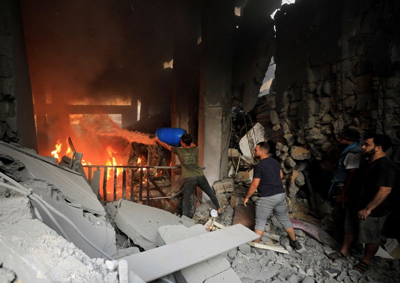 &copy; Reuters. فلسطينيون يحاولون إخماد النيران عقب تعرض مبنى سكني في مدينة غزة لقصف إسرائيلي في يوم 25 أكتوبر تشرين الأول 2023 . تصوير : ياسر قديح - رويترز . 