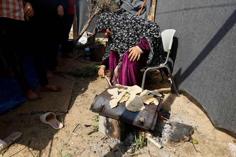 &copy; Reuters. امرأة تعد الطعام في مخيم بمركز تديره الأمم المتحدة جنوب قطاع غزة يوم 23 أكتوبر تشرين الأول 2023. تصوير: إبراهيم أبو مصطفى - رويترز.