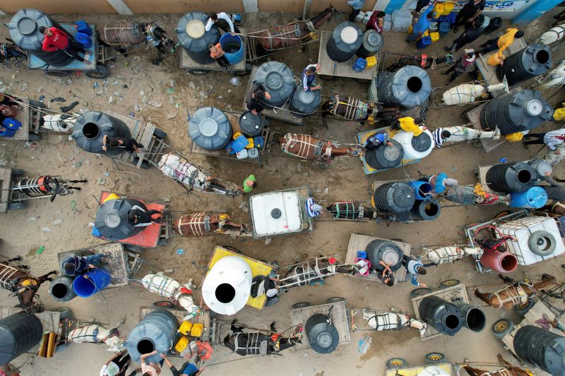 &copy; Reuters. Palestinians with animal-drawn carts collect water from a water desalination plant, amid water shortages, as the conflict between Israel and the Palestinian Islamist group Hamas continues, in central Gaza Strip October 27, 2023. REUTERS/Mohammed Fayq Abu 