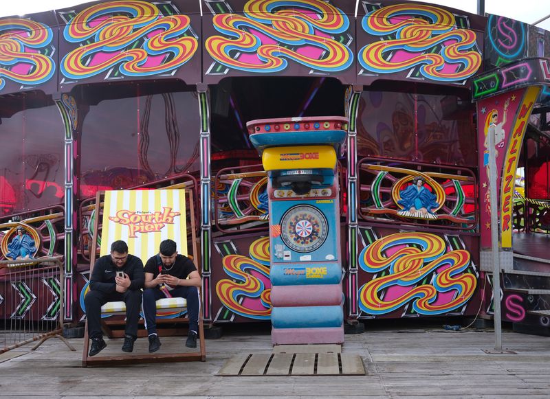 &copy; Reuters. Youths look at their mobile phones as they sit in a giant deckchair on the South Pier following the outbreak of the coronavirus disease (COVID-19) in Blackpool, Britain, August 16, 2020. Picture taken August 16, 2020. REUTERS/Phil Noble/File Photo
