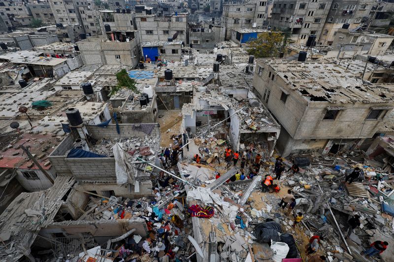 &copy; Reuters. أفراد بطواقم الإسعاف وأشخاص يتفقدون آثار الدمار بموقع تعرض لغارات جوية إسرائيلية على المنازل في مدينة خان يونس جنوب قطاع غزة يوم الأحد. تصو
