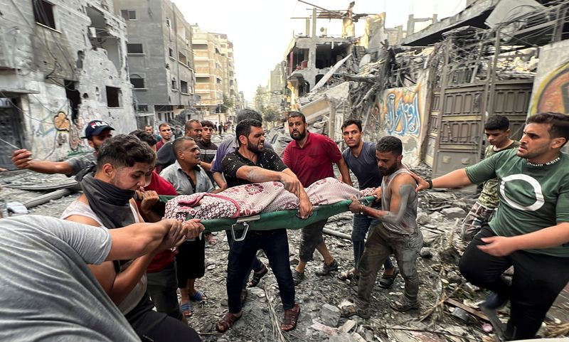 &copy; Reuters. Des Palestiniens portent un blessé sur le site de frappes israéliennes sur des maisons, dans la ville de Gaza. /Photo prise le 28 octobre 2023/REUTERS/Mutasem Murtaja