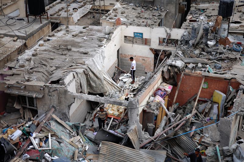 &copy; Reuters. فلسطينيون بتفقدون الدمار الذي لحق بمنازل تعرضت لغارات إسرائيلية في خان يونس جنوب قطاع غزة يوم الأحد. تصوير: محمد سالم - رويترز.