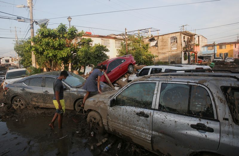 © Reuters. A woman climbs over a car stuck in the mud, in the aftermath of Hurricane Otis, in Acapulco, Mexico, October 29, 2023. REUTERS/Quetzalli Nicte-Ha