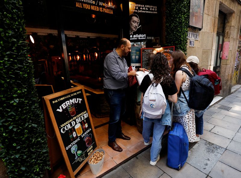 &copy; Reuters. Un cameriere mostra il menu a due turisti nel quartiere di Raval a Barcellona. 24 maggio 2023. REUTERS/Albert Gea/File Photo