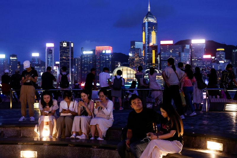 &copy; Reuters. FILE PHOTO: Tourists relax on the waterfront in front of Victoria Harbour, with the iconic skyline buildings as a backdrop, in Hong Kong, China June 28, 2023. REUTERS/Tyrone Siu/File Photo
