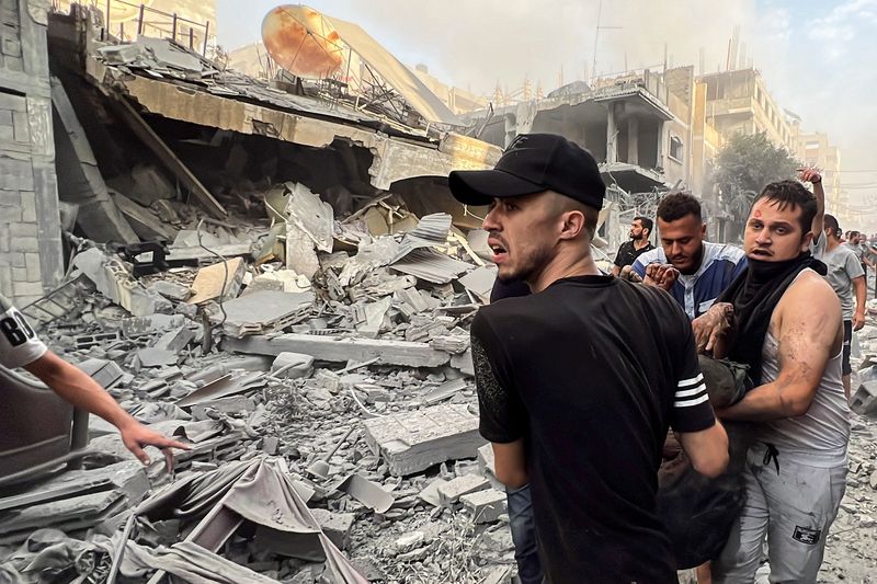 &copy; Reuters. فلسطينيون يحملون مصابا بموقع منازل تعرض لغارات إسرائيلية في مدينة غزة يوم 28 أكتوبر تشرين الأ,ل 2023. تصوير: معتصم مرتجى - رويترز.