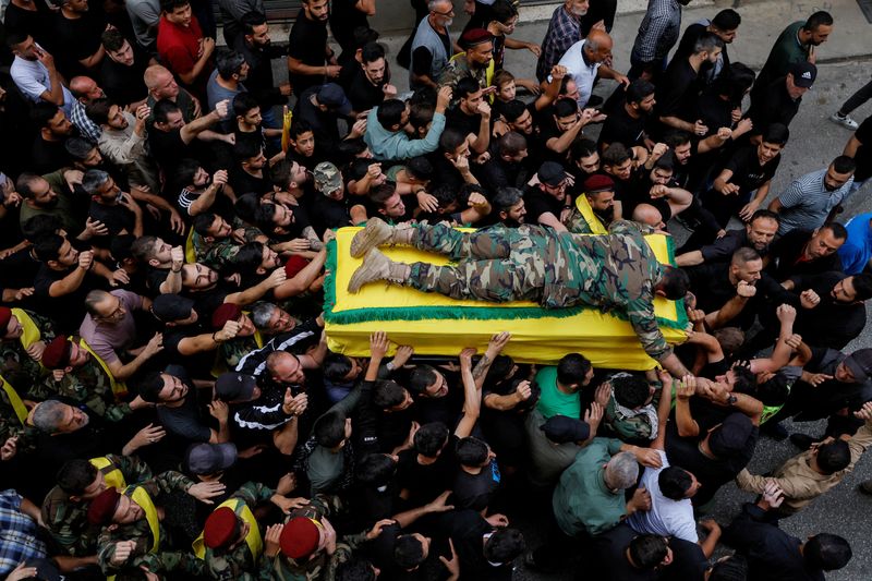 &copy; Reuters. نزيه، نجل عضو حزب الله اللبناني منير يوسف عاشور الذي قتل في جنوب لبنان وسط التوتر بين الحزب وإسرائيل، يستلقي على نعش والده أثناء تشييع جثمان