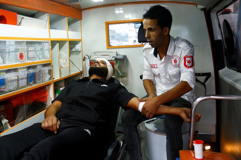 © Reuters. مسعف فلسطيني متطوع يساعد رجلا في سيارة إسعاف أصيب في غارة إسرائيلية على مستشفى ناصر في خان يونس بجنوب قطاع غزة يوم 29 أكتوبر تشرين الأول 2023. تصوير: إبراهيم أبو مصطفى - رويترز.