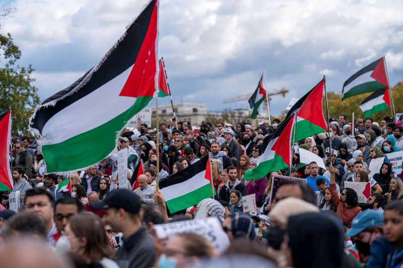 © Reuters. People raise flags and posters during a rally held by American Muslims for Palestine calling for a cease fire in Gaza near the Washington Monument in in Washington, U.S., October 21, 2023.  REUTERS/Bonnie Cash