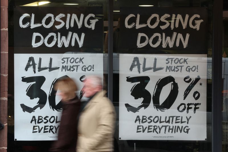 &copy; Reuters. FILE PHOTO: People walk past a shop with closing down signs in the window in Chester, Britain, November 17, 2022. REUTERS/Phil Noble/File Photo