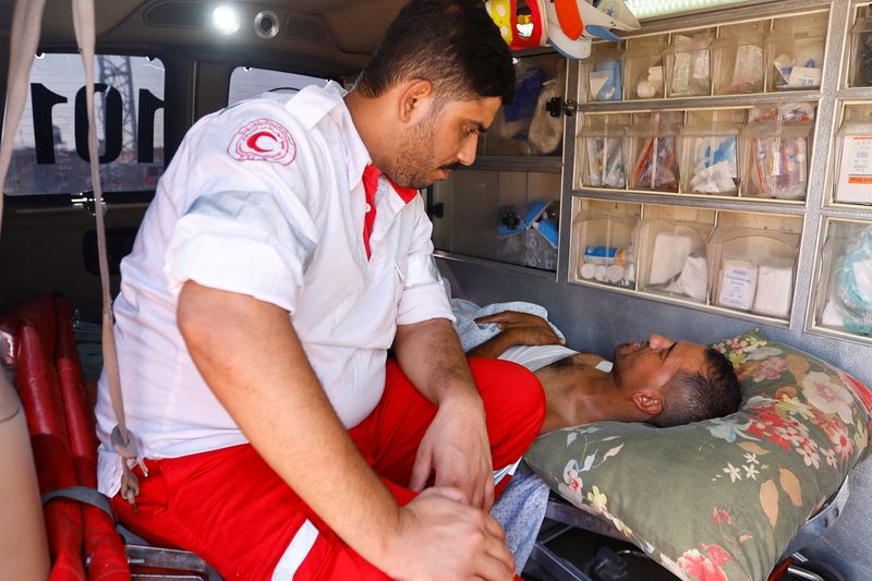 &copy; Reuters. موظف في القطاع الطبي بجوار مصاب فلسطيني سيتلقى العلاج في مستشفى مصري عند معبر رفح الحدودي مع مصر في جنوب قطاع غزة يوم الأربعاء. تصوير: إبراهي