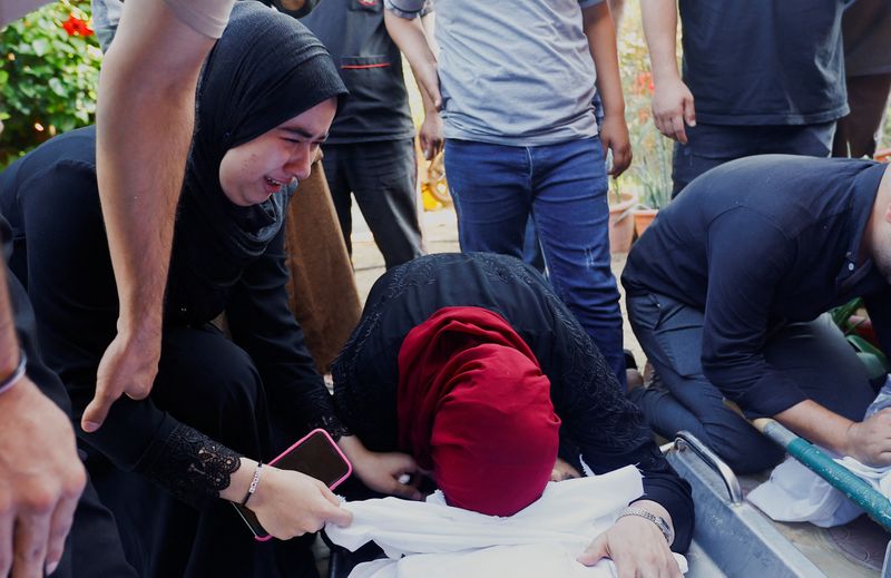 &copy; Reuters. مشيعون يبكون بجوار جثث فلسطينيين قتلوا في غارات إسرائيلية خلال جنازة في خان يونس بجنوب قطاع غزة يوم الثلاثاء. تصوير: إبراهيم أبو مصطفى - رويت