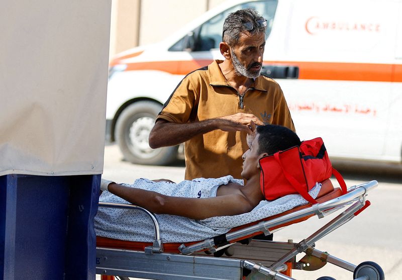 &copy; Reuters. رجل يقف بجوار مصاب فلسطيني سيتلقى العلاج في مستشفى مصري عند معبر رفح الحدودي مع مصر في جنوب قطاع غزة يوم الأربعاء. تصوير: إبراهيم أبو مصطفى - 