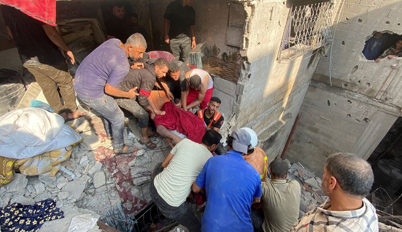 &copy; Reuters. مواطنون ينتشلون جثة أحد ضحايا القصف الإسرائيلي على منزل في خان يونس بجنوب قطاع غزو يوم الأربعاء . تصوير : بسام مسعود - رويترز .  