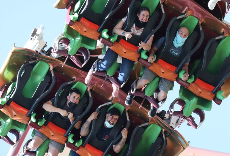 &copy; Reuters. People ride a roller coaster at Six Flags Magic Mountain amusement park on the first day of opening, as the coronavirus disease (COVID-19) continues, in Valencia, California, U.S., April 1, 2021. REUTERS/Lucy Nicholson