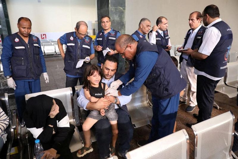 © Reuters. أطباء بالحجر الصحي في مصر يقومون بإجراء فحوصات طبية لحاملي جوازات السفر الأجنبية بعد وصولهم إلي معبر رفح قادمين من غزة يوم الأربعاء .صورة لرويترز من وزارة الصحة المصرية.
