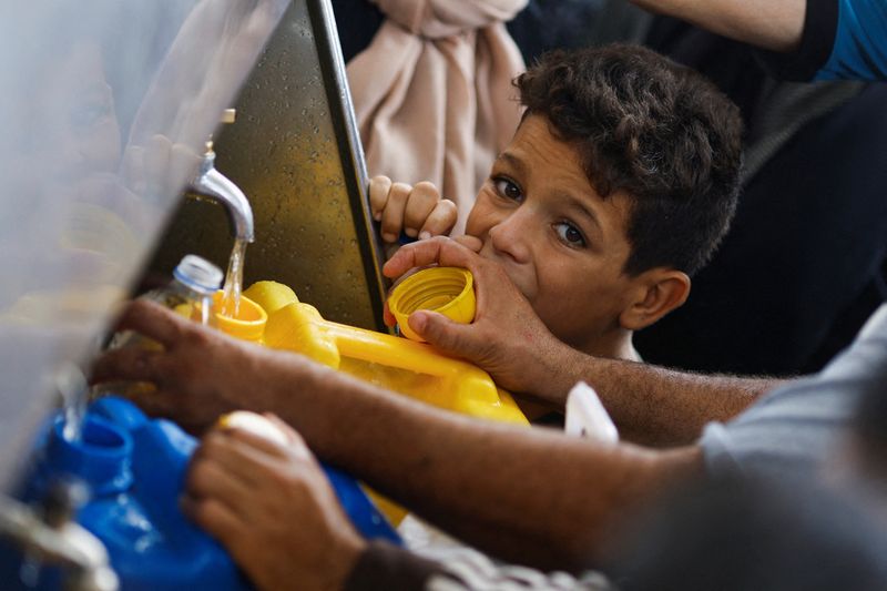 &copy; Reuters. طفل ينظر بينما يتجمع فلسطينيون للتزود بالمياه وسط نقص المياه النظيفة في قطاع غزة يوم الخميس. تصوير:محمد سالم -رويترز.
