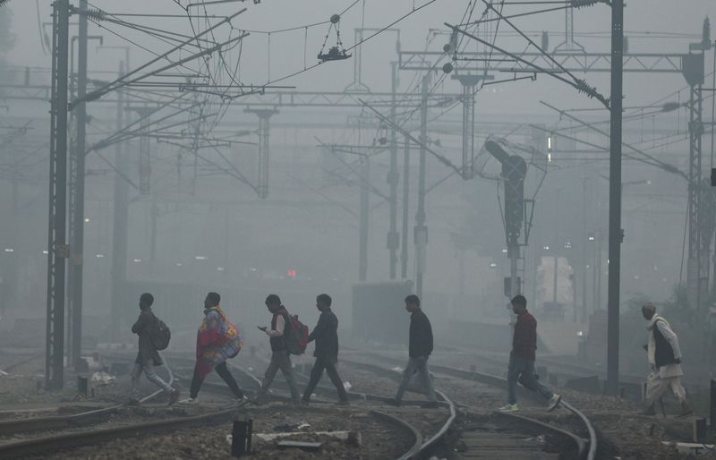&copy; Reuters. أشخاص يعبرون شريط السكك الحديدية صباح يوم الجمعة وسط ضباب كثيف بمدينة نيودلهي في الهند . تصوير : أنوشري فادنافيز - رويترز .  