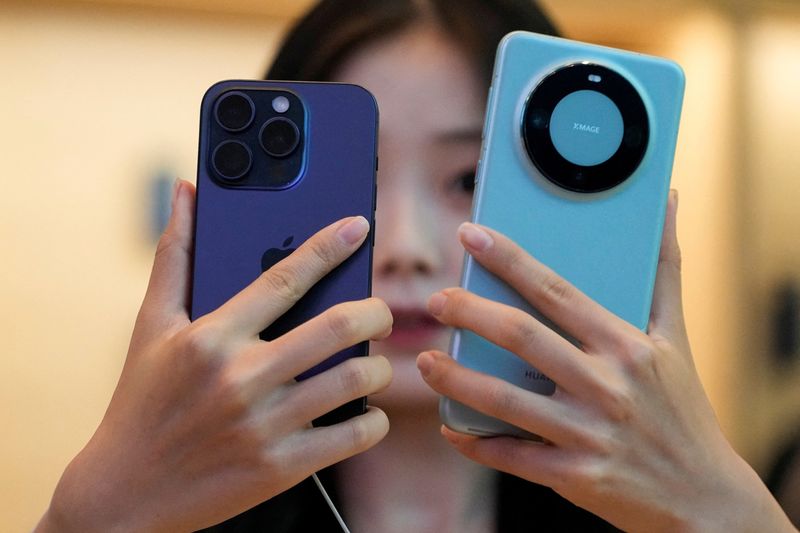 &copy; Reuters. FOTO DE ARCHIVO: Una mujer mira un nuevo iPhone 15 Pro y un Huawei Mate 60 Pro en el momento en que el nuevo iPhone 15 de Apple sale oficialmente a la venta en toda China, en una tienda de Apple en Shanghái, China 22 de septiembre de 2023. REUTERS/Aly So