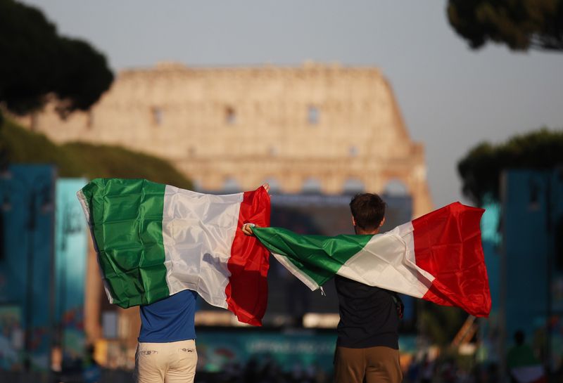 &copy; Reuters. Due persone con bandiere italiane di fronte al Colosseo. 11 luglio 2021. REUTERS/Yara Nardi