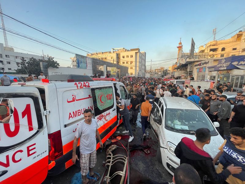 © Reuters. فلسطينيون يتحققون من الأضرار بعد قصف قافلة سيارات إسعاف عند مدخل مستشفى الشفاء في مدينة غزة يوم الجمعة. تصوير: محمد المصري - رويترز.