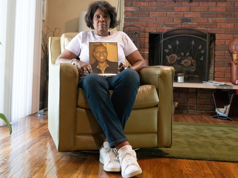 © Reuters. Sheila Bush, who is among women who have filed thousands of lawsuits against cosmetic companies alleging they sold hair relaxers associated with increased risk of uterine cancer, poses for a picture in her living room holding a photo of her with cancer, in St. Louis, Missouri, U.S., September 26, 2023. REUTERS/Lawrence Bryant