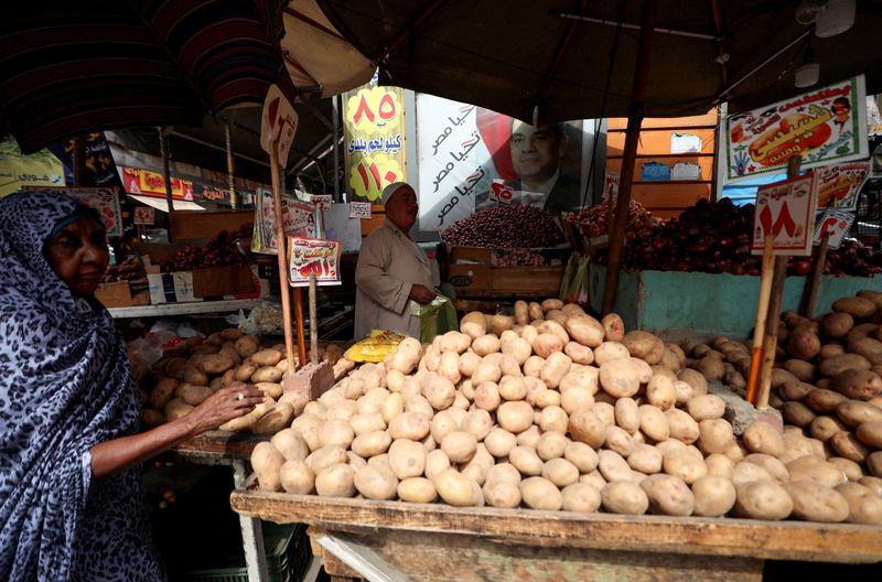 &copy; Reuters. شخص يشتري الخضروات من أحد الأسواق بينما تظهر في الخلفية لافتة عليها صورة الرئيس المصري عبد الفتاح السيسي في القاهرة بتاريخ التاسع من أكتوبر