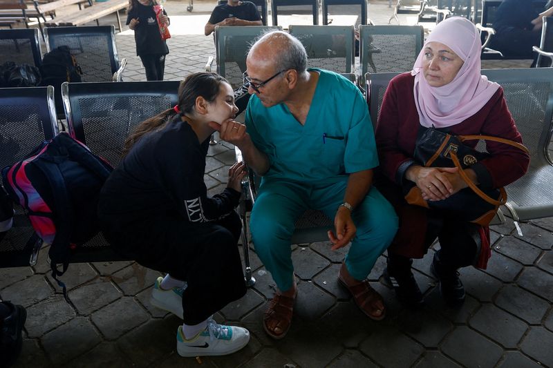 &copy; Reuters. الطبيب الفلسطيني محمد أبو ناموس، الذي قرر البقاء في القطاع لرعاية آلاف الجرحى جراء القصف الإسرائيلي، يودع أسرته عند معبر رفح في قطاع غزة يو