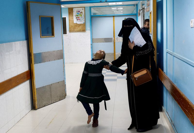 &copy; Reuters. A Palestinian woman helps a school girl walk at the X-ray unit in Shifa hospital in Gaza City, January 5, 2023. REUTERS/Ibraheem Abu Mustafa  