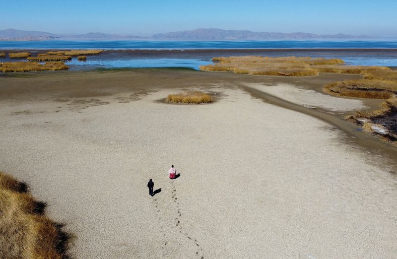 &copy; Reuters. FOTO DE ARCHIVO: Gabriel Flores e Isabel Apaza caminan sobre el lecho seco agrietado cerca de la orilla del lago Titicaca en época de sequía en Huarina, Bolivia. 3 de agosto de 2023. REUTERS/Claudia Morales