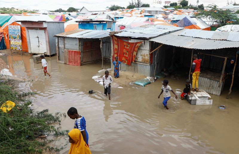 &copy; Reuters. أطفال صوماليون يسيرون في مياه الفيضانات خارج ملاجئهم المؤقتة عقب هطول أمطار غزيرة في مخيم للنازحين بالقرب من مقديشو في الصومال يوم السادس م