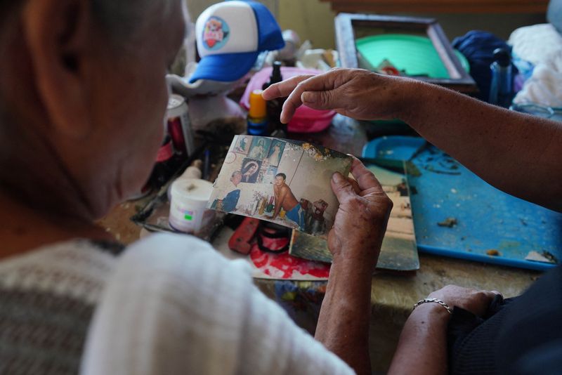 © Reuters. Manuela Garcia, 69, mother of Hugo Garcia, a fisherman who died during Hurricane Otis in Acapulco, Mexico, shows a picture of them together to a friend in their home, October 30, 2023. REUTERS/Alexandre Meneghini