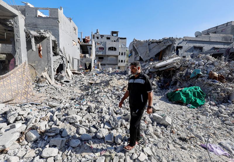 &copy; Reuters. الفلسطيني محمد حمدان الذي فقد 35 شخصا من أفراد أسرته في غارة جوية إسرائيلية يسير وسط أنقاض منزل العائلة في خان يونس جنوب قطاع غزة يوم الثلاثا