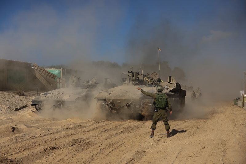 &copy; Reuters. جندي إسرائيلي يلوح في أثناء تحرك مركبات عسكرية خلال الاشتباك بين إسرائيل وحماس في شمال غزة يوم الثلاثاء. تصوير: رونين زفولون - رويترز.