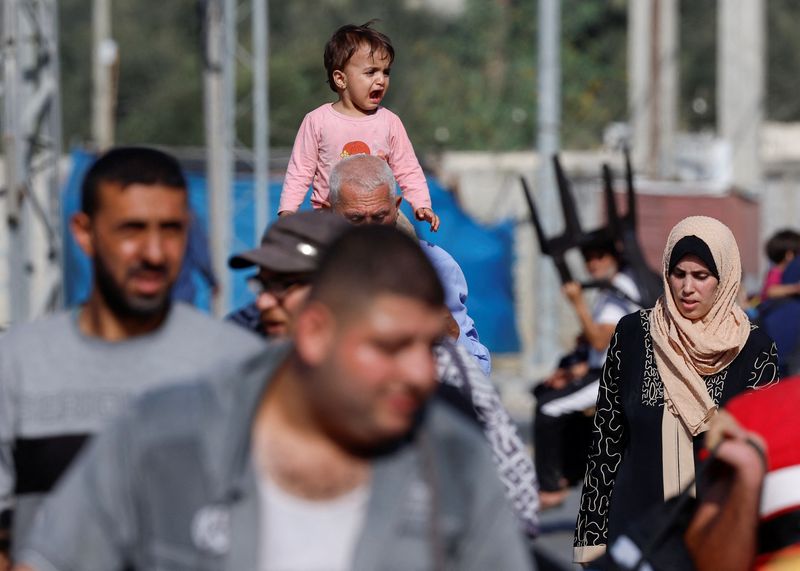 &copy; Reuters. Un uomo porta un bambino sulle spalle, tra i palestinesi che, in fuga dal nord di Gaza, si dirigono verso il sud, nel corso del conflitto in corso tra Israele e il gruppo islamista palestinese Hamas, nella Striscia di Gaza centrale, 9 novembre 2023. REUTE