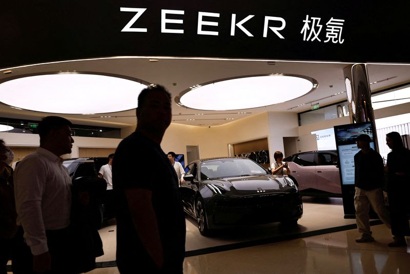 &copy; Reuters. FILE PHOTO: People walk past a booth of Zeekr, Chinese automaker Geely's premium electric vehicle (EV) brand, at a shopping mall in Beijing, China November 3, 2023. REUTERS/Tingshu Wang/File Photo