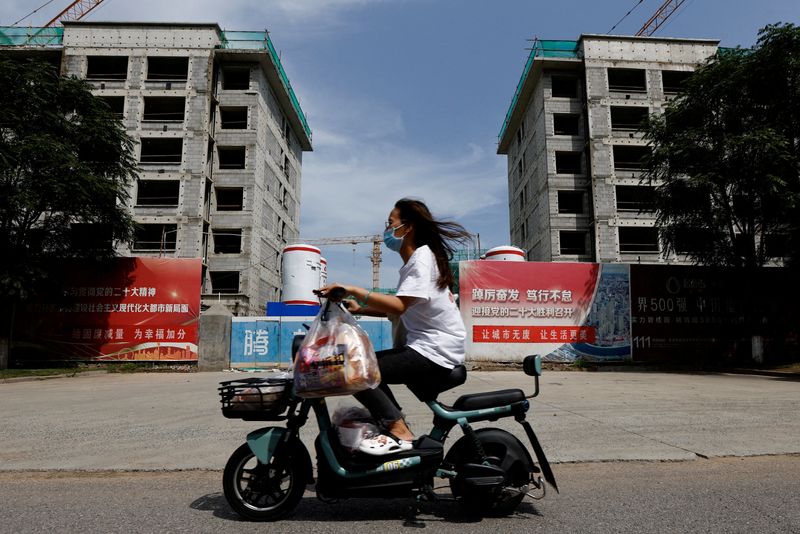 © Reuters. A person rides a scooter past a construction site of residential buildings by Chinese developer Country Garden, in Tianjin, China August 18, 2023. REUTERS/Tingshu Wang