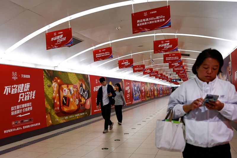 &copy; Reuters. FILE PHOTO: People walk past Alibaba's advertisements promoting Singles Day shopping festival, at a subway station in Beijing, China October 26, 2023. REUTERS/Tingshu Wang