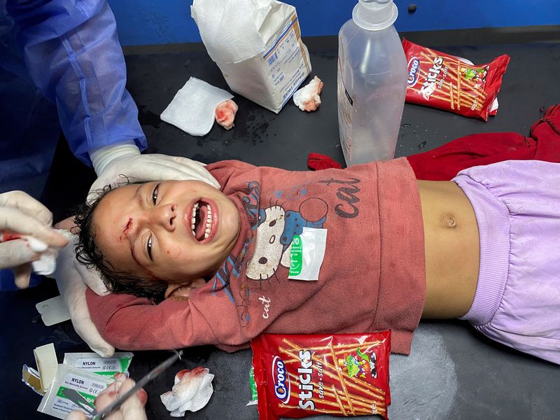 &copy; Reuters. طفلة فلسطينية تصرخ أثناء قيام أحد الممرضين بخياطة جرح في جبهتها دون استخدام مخدر في مستشفى الشفاء بمدينة غزة في الثامن من أكتوبر تشرين الأو