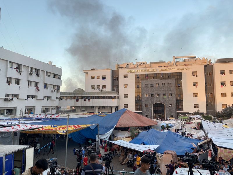 &copy; Reuters. أعمدة دخان تتصاعد في سماء غزة بينما يتخذ فلسطينيون نازحون من مستشفى الشفاء ملجأ لهم في الثامن من نوفمبر تشرين الثاني 2023. تصوير: دعاء روقة - رو