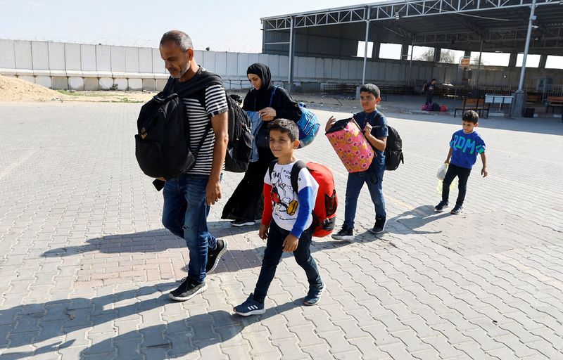 &copy; Reuters. أفراد أسرة فلسطينية ، بينهم  حاملو جوازات سفر أجنبية، يحملون أمتعتهم ينتظرون عند معبر رفح البري في جنوب قطاع غزة استعدادا للدخول إلى مصر في 