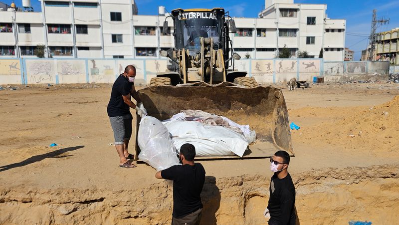 &copy; Reuters. جرافة تنقل جثامين مجهولة الهوية لفلسطينيين قتلوا جراء غارات إسرائيلية تمهيدا لدفنهم في مقابر جماعية في شمال قطاع غزة يوم السبت . تصوير : أنس 