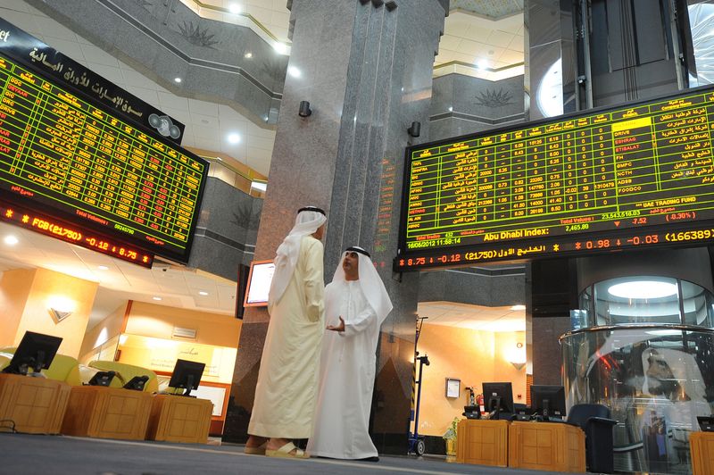&copy; Reuters. متداولون يقفون بالقرب من شاشات إلكترونية تعرض حركة أسهم البورصة في بورصة أبوظبي لتداول الأوراق المالية. الصورة من أرشيف رويترز 