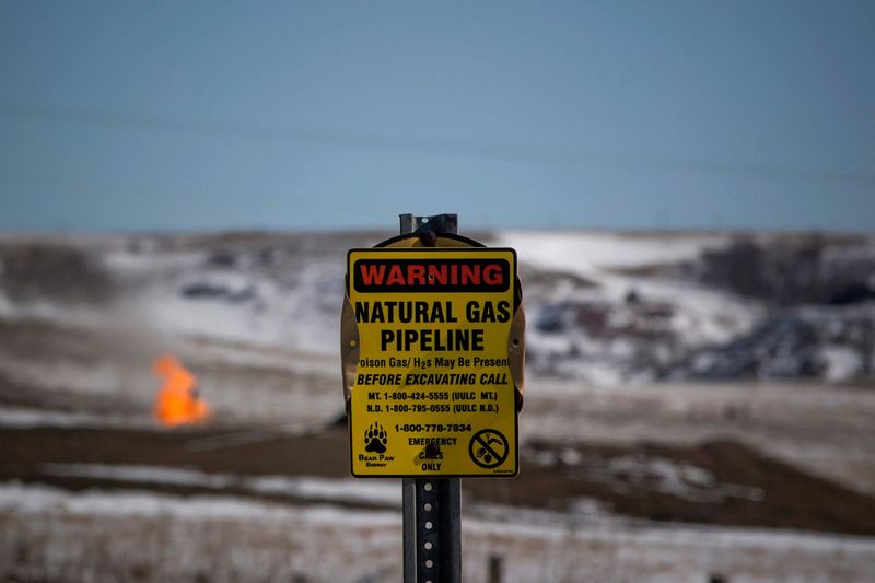 &copy; Reuters. FILE PHOTO: A warning sign for a natural gas pipeline is seen as natural gas flares at an oil pump site outside of Williston, North Dakota March 11, 2013.   REUTERS/Shannon Stapleton/File Photo