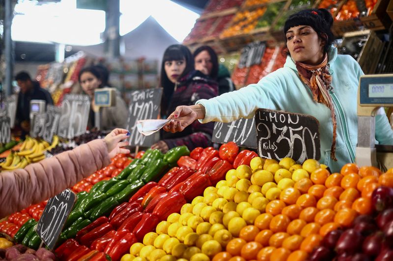 &copy; Reuters. A saleswoman gives change to a customer at a greengrocer's shop at the Mercado Central, the city's largest wholesale central market, which receives produce from the entire country, as Argentines face a daily race for deals as inflation soars above 100%, o