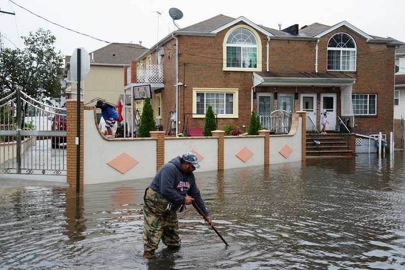 &copy; Reuters. A resident surnamed Mahamad, a driving instructor and bus driver, attempts to unclog leaves and other debris from drainage holes in the flooded street of Rau Court, as the remnants of Tropical Storm Ophelia bring flooding across the mid-Atlantic and North