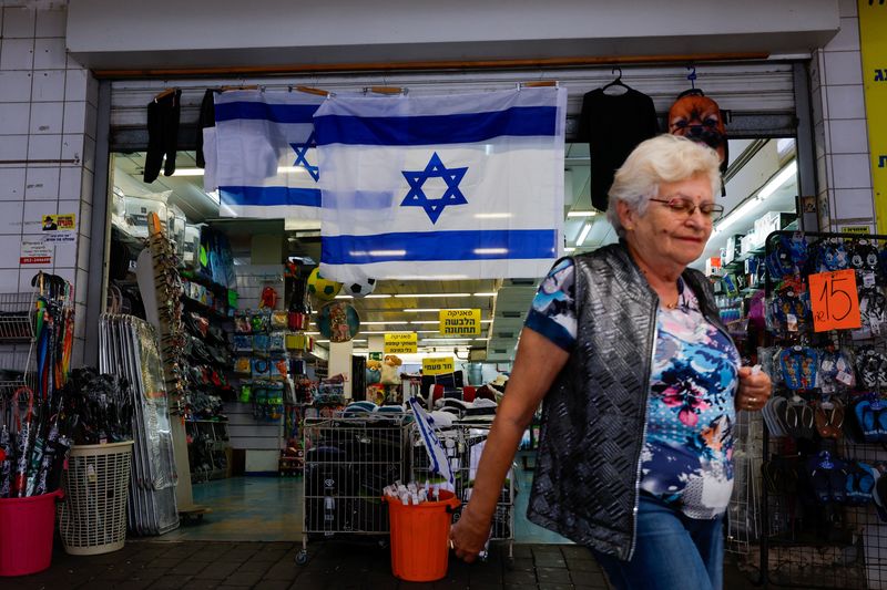 © Reuters. File photo: A local woman passes by a shop that displays an Israeli flag in the city of Tiberias, Israel, November 8, 2023. REUTERS/Alexander Ermochenko/File photo