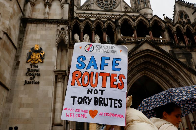 &copy; Reuters. FILE PHOTO: A protestor holds a placard while demonstrating outside the High Court over the legal challenge against the government's policy to deport illegal immigrants to Rwanda in London, Britain December 19, 2022. REUTERS/Peter Nicholls/File Photo
